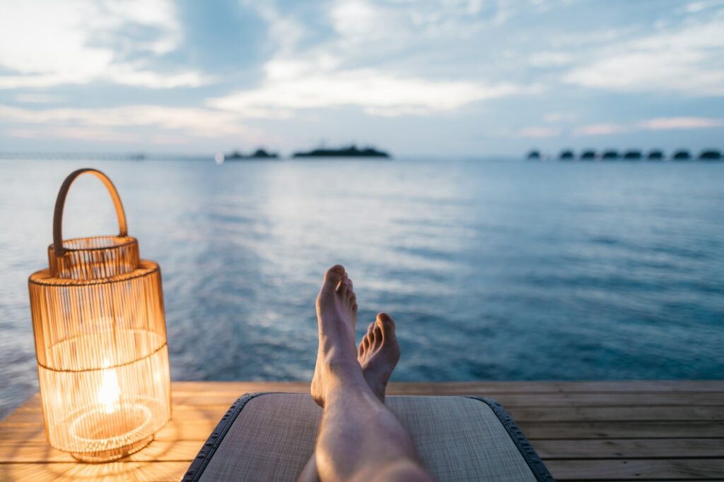 person lying on chair and facing on body of water