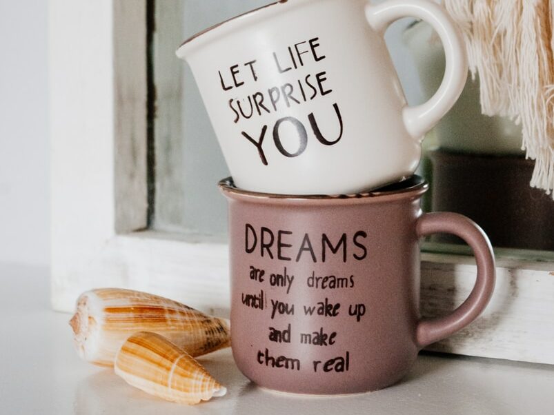 white and black ceramic mug on brown wooden table