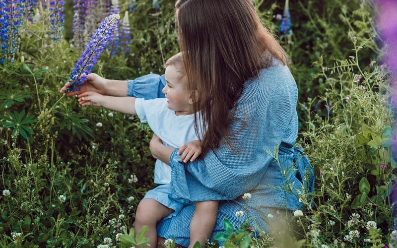 woman sitting with baby on her lap surrounded with purples flower